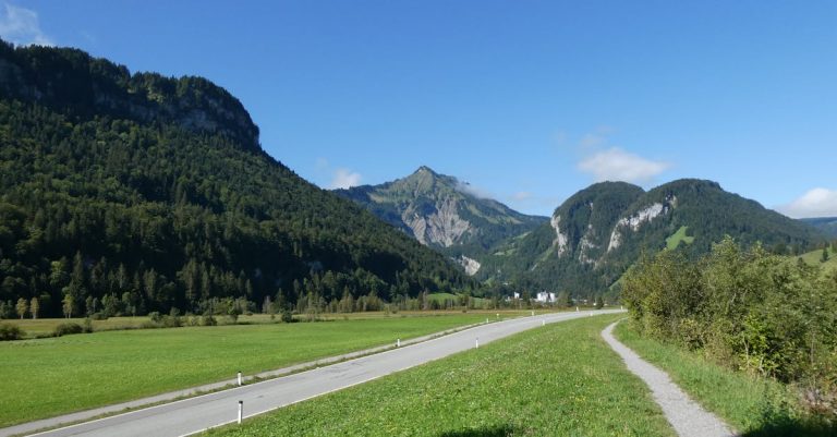 Breathtaking view of a valley surrounded by lush mountains under a clear blue sky.
